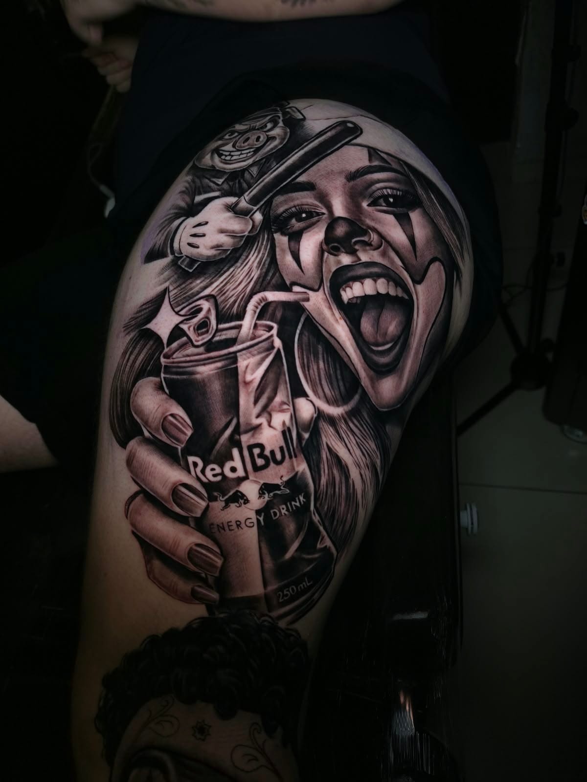 Tatuagem na perna com rosto feminino sorrindo, lata de energético e personagem com bastão