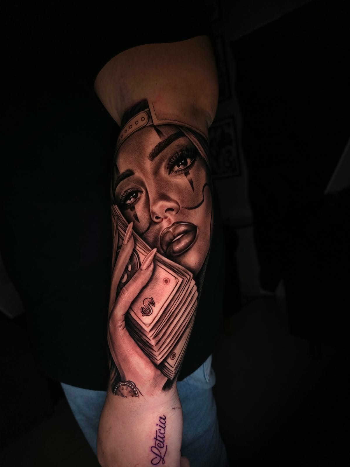 Tatuagem de rosto feminino com boné, maquiagem de palhaça e notas com cifrão no braço